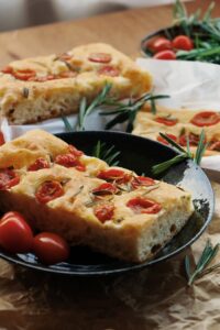 Delicious slices of rosemary and tomato focaccia on a rustic table.