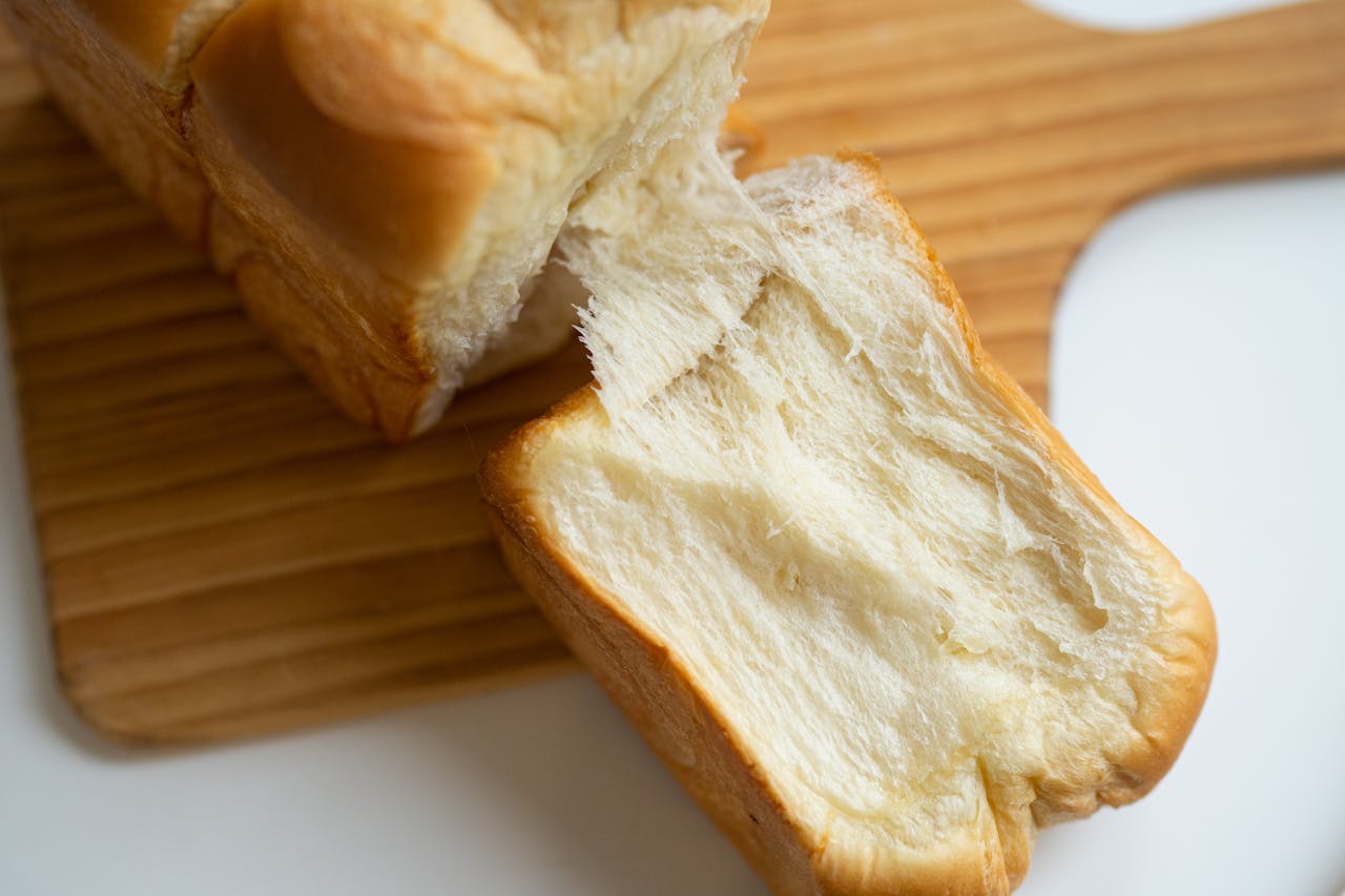 Close-up of soft, fluffy bread loaf on a wooden board, highlighting texture and freshness.